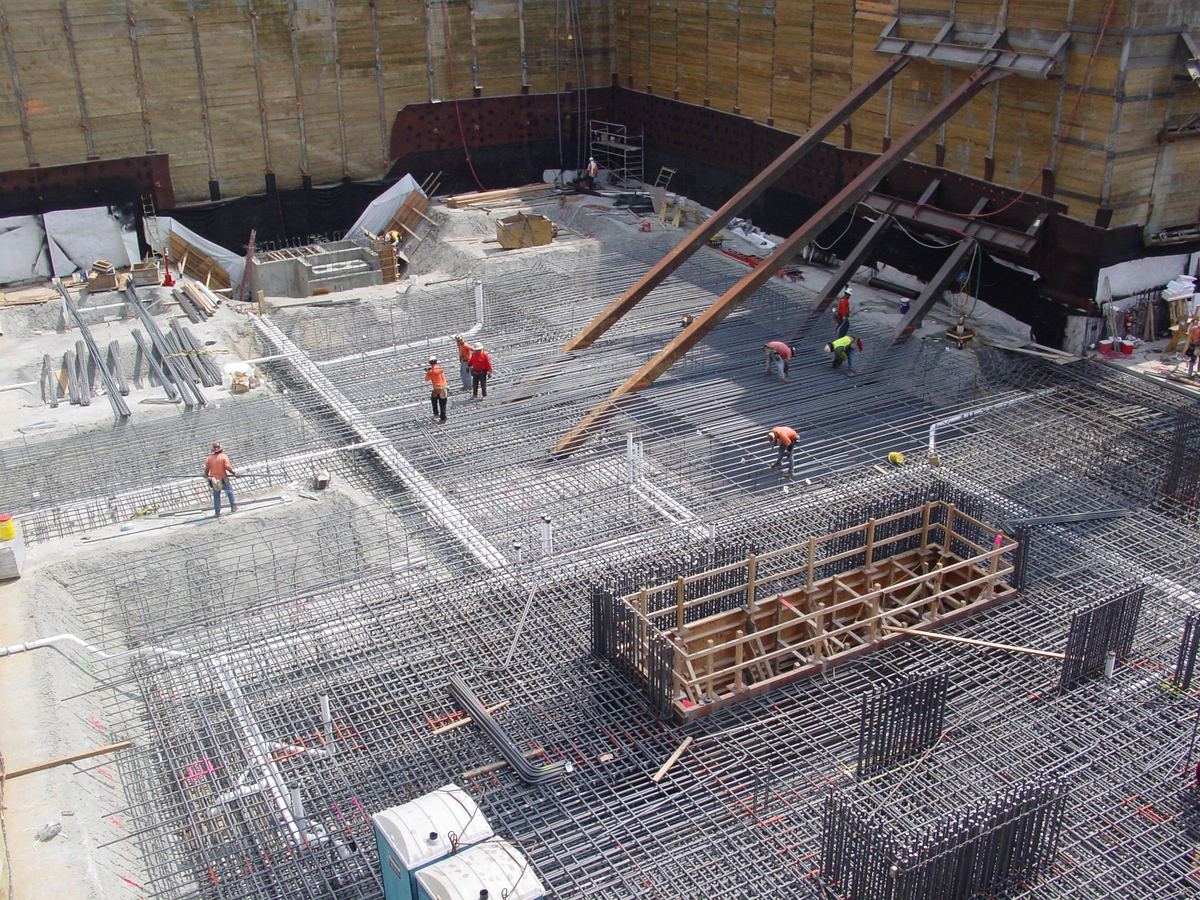 Steel contractors working over a waterproofing system on a job site.