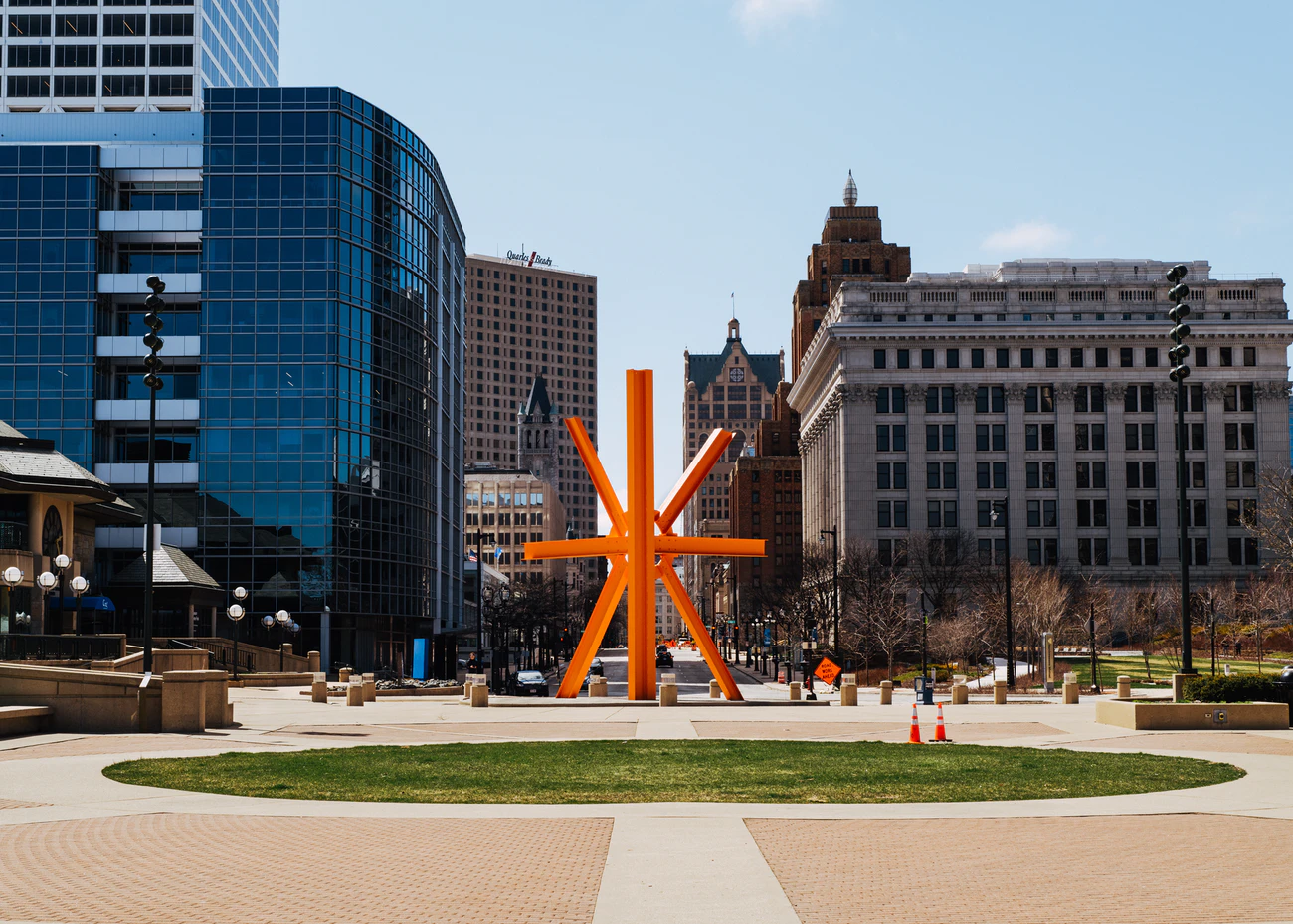 Cityscape with sidewalk and orange art installation.