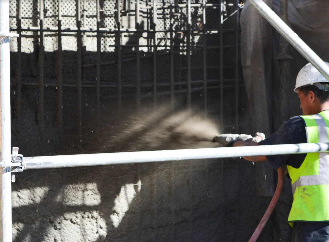 Construction worker applying sprayed concrete.